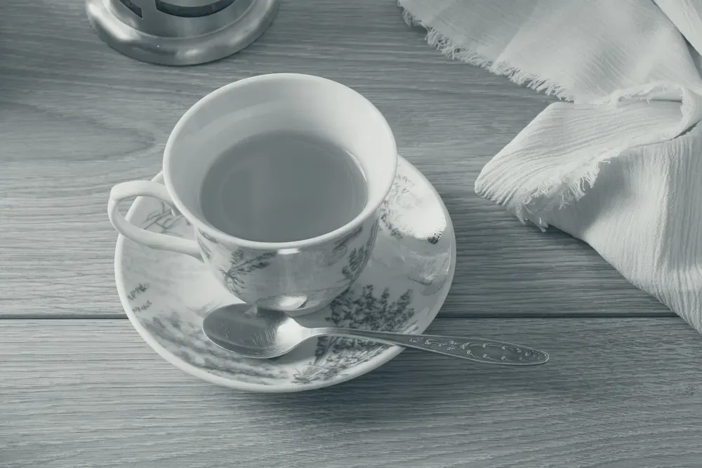 A teacup on a floral saucer on a light wooden table in a home setting.