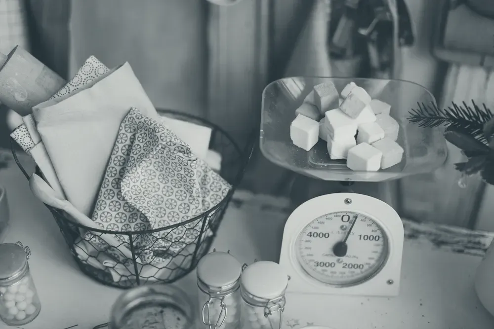 An analog kitchen scale with a dial in grams, weighing marshmallow cubes.