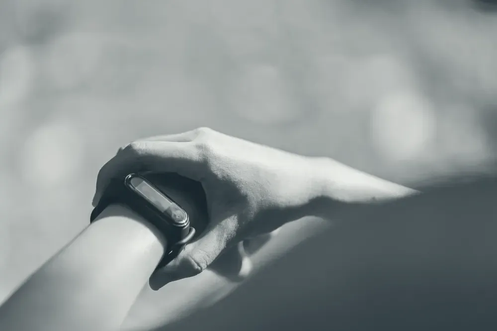 A heart rate monitor band on a wrist, in direct sunlight with a sharp shadow.