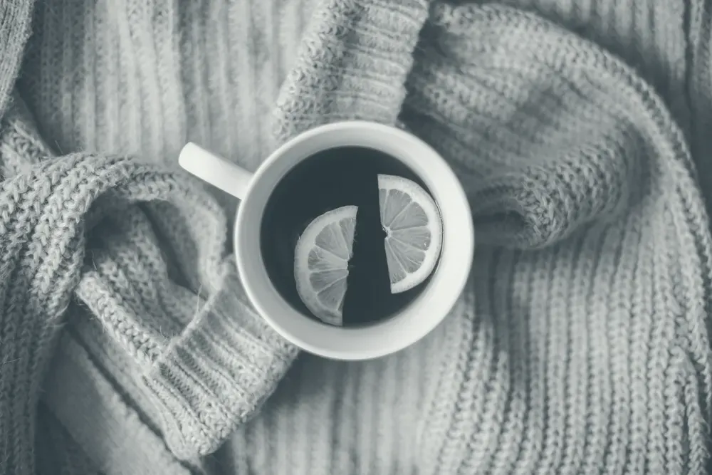 A cup of tea with lemon slices, seen from above on soft knitted fabric.