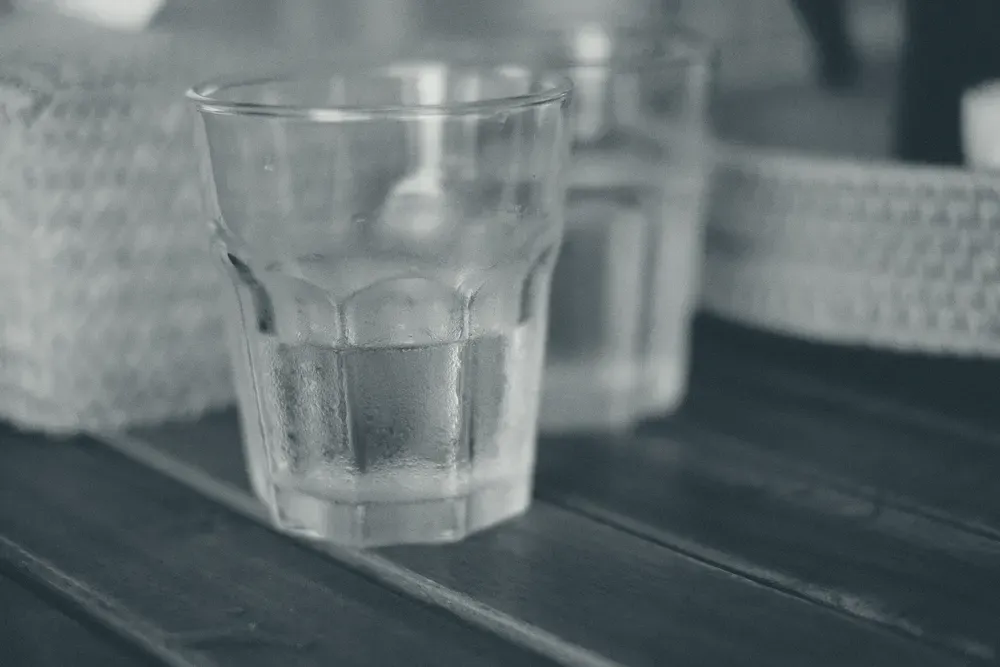 A glass of iced water beaded with condensation on a wooden table.