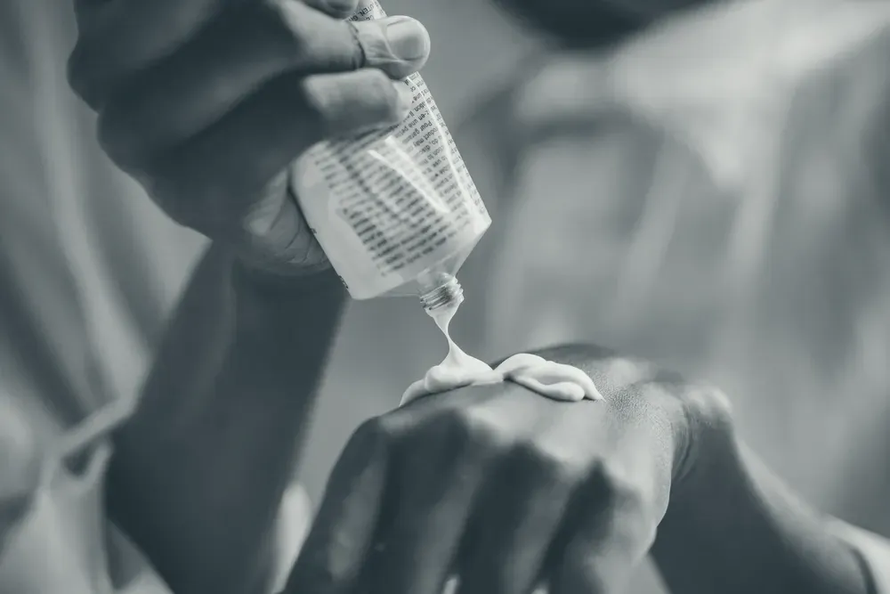 Moisturizer being smoothed over the skin of the hands, with natural texture and shadow.